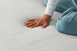 woman's hand pressing down on adapt mattress topper