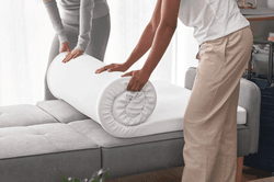 tempurpedic mattress topper being rolled onto couch